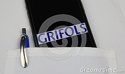 Close up of mobile phone screen with logo lettering of Grifols pharmaceutical company in pocket of white doctors coat with pencil Editorial Stock Photo