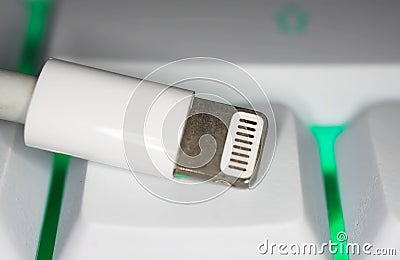 Top down view closeup of one isolated Apple lightning data and power connector with eight pins on computer keyboard Editorial Stock Photo