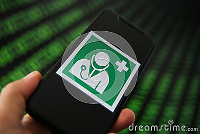 Central health data storage management concept: View on mobile phone with international doctor health sign. Blurred binary numbers Editorial Stock Photo