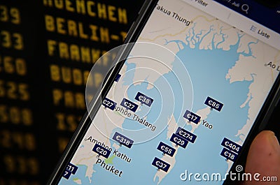 Closeup of mobile phone with hotel booking app. Blurred departure board background. Editorial Stock Photo