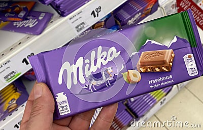 View on hand holding Milka chocolate nut bar in german supermarket Editorial Stock Photo