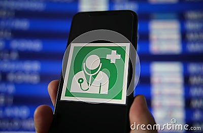 Viersen, Germany - July 9. 2020: View on hand holding mobile phone with green sign for health and medical assistance at airport. Editorial Stock Photo