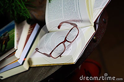 View on open book with red reading glasses and stack of travel books Editorial Stock Photo