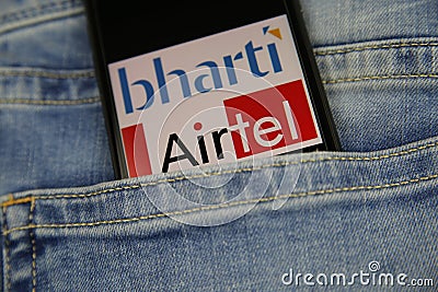 Close up of smartphone screen in blue jeans pocket with logo lettering of indian mobile phone provider bharti Airtel Editorial Stock Photo