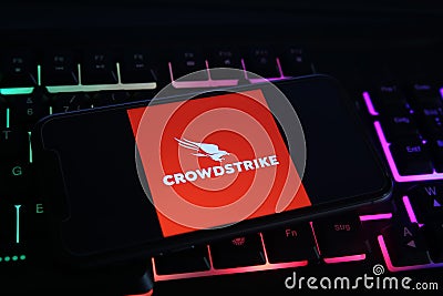 Closeup of mobile phone screen with logo lettering of crowdstrike cyber security company on computer keyboard focus on upper part Editorial Stock Photo