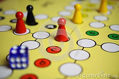 Closeup of yellow game board with colorful pieces and dice of mensch Ã¤rgere dich nicht Stock Photo