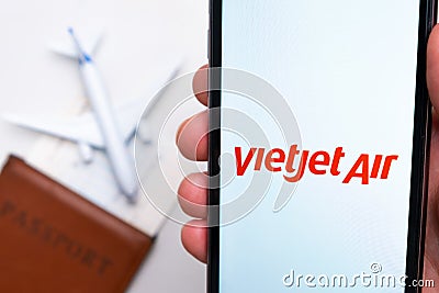 VietJet Air Airline app on a smartphone screen with a plane and passport on the background. The concept of travel app Editorial Stock Photo