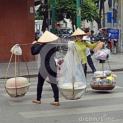  women street vendors with coolie hats and baskets carried on bamboo poles, Hanoi Vietnam Editorial Stock Photo