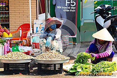 Vietnam, Phu Quoc Island, 26 February 2018: Unidentified women with typical vietnamese conical hats sell fresh food on a Editorial Stock Photo