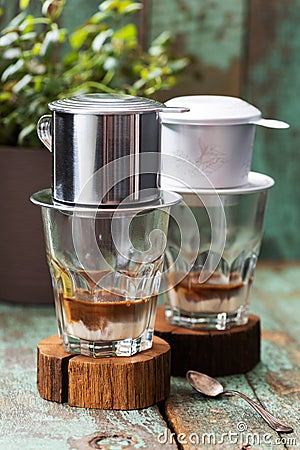 Vietnamese coffee in glass cups on old boards, phin filter and green grass background Stock Photo