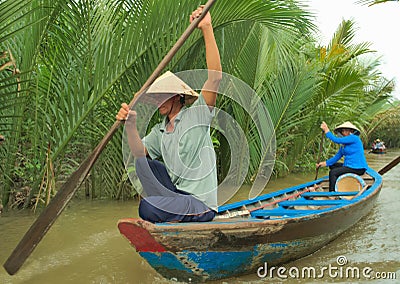 Vietnamese couple rowing on a boat along one of the tributaries of Mekong River near My Tho, Vietnam. Editorial Stock Photo