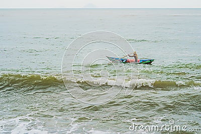 Vietnamese fisherman swims in a boat over the raging sea Editorial Stock Photo