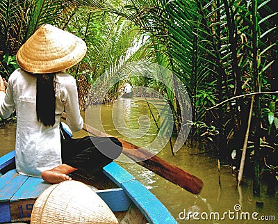 A Vietnamese lady in traditional conical hat, sits on her wooden boat in the Mekong Delta, near Ho Chi Minh city, Vietnam Editorial Stock Photo