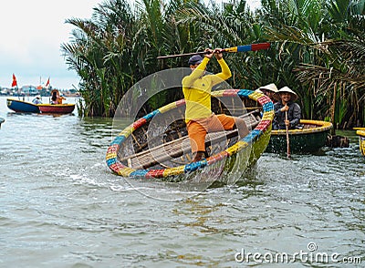 A Vietnamese man is dancing on colorful basket boat Editorial Stock Photo