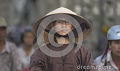 Vietnamese monk wears a specific Vietnamese hat in the street traffic of Hue city. Editorial Stock Photo