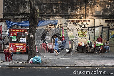 Vietnamese residents enjoy a quiet moment on the street by an old wall in Ho Chi Minh City, Vietnam Editorial Stock Photo