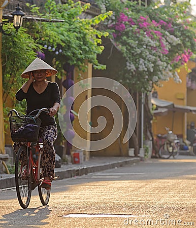 Vietnamese woman bicycling in Hoi An Editorial Stock Photo