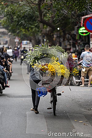 Vietnamese woman with bike selling flowers on the street market of old town in Hanoi, Vietnam Editorial Stock Photo
