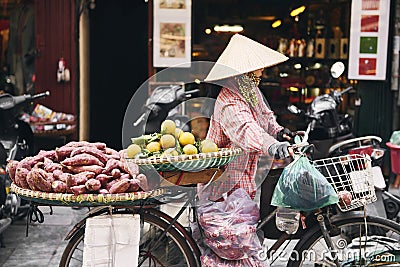 Vietnamese woman with bike selling tropical fruit at the market Editorial Stock Photo