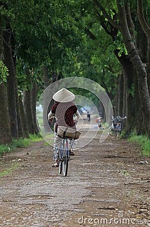 Vietnamese woman cycling on a country road Editorial Stock Photo