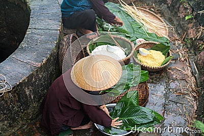 Vietnamese woman preparing to make Chung Cake, the Vietnamese lunar new year Tet food outdoor by old well and pond Stock Photo