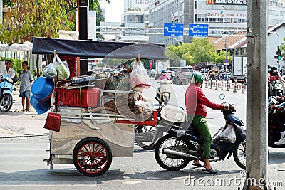 Vietnamese woman ride motorbike pull food cart stop on street Editorial Stock Photo