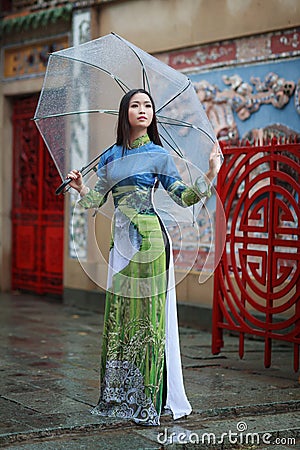 Vietnamese women wear Ao dai holding umbrella in the rain Stock Photo