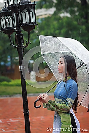 Vietnamese women wear Ao dai holding umbrella in the rain Stock Photo