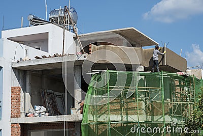 Vietnamese worker smooths concrete wall on top a condo being built in Ho Chi Minh City, Vietnam Editorial Stock Photo