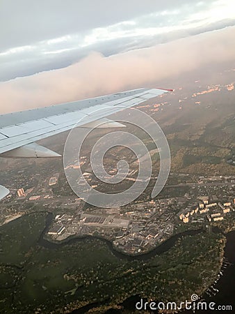 A view from above of the city with buildings, houses from the porthole, aircraft windows on the wing with engines, turbines and wh Stock Photo