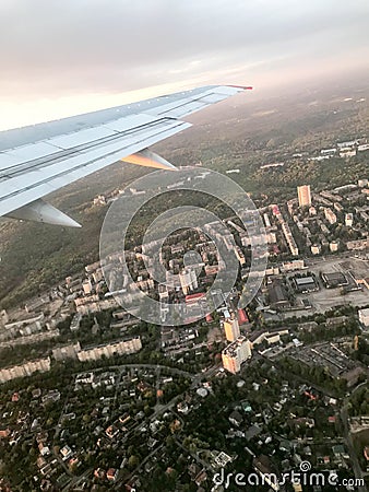 A view from above of the city with buildings, houses from the porthole, aircraft windows on the wing with engines, turbines and wh Stock Photo