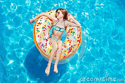 Teen girl swim in pool on inflatable doughnut Stock Photo