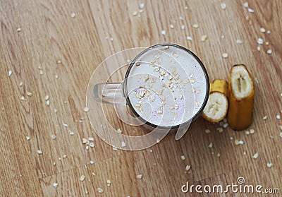 A glass of milkshake with a banana and oatmeal and marshmallows isolated on a wooden background. Stock Photo