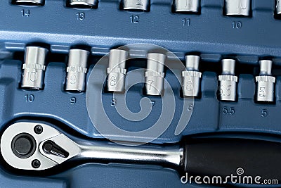 View from above of ratchet wrench and some stainless steel hex sockets on blue background Stock Photo