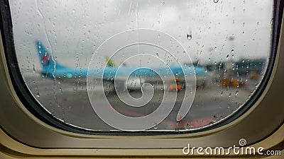 View from an airplane eluminator with raindrops on a blue plane standing next to the runway at the airport in Seoul. Stock Photo