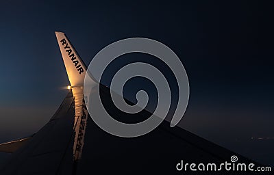 View through an airplane window onto the wing of an Ryanair Boeing 737-800 airplane with winglets in flight during sunset Editorial Stock Photo