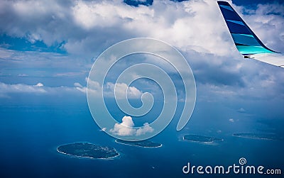 View from airplane window trough clouds at tropical island Stock Photo