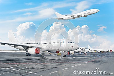 View of the airport aircraft parking at the terminal, and a plane taking off in the sky with clouds. Stock Photo
