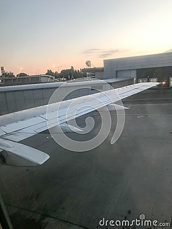 View of the airport, hangars from the porthole, the windows of the aircraft on the wing with engines, turbines after landing Stock Photo