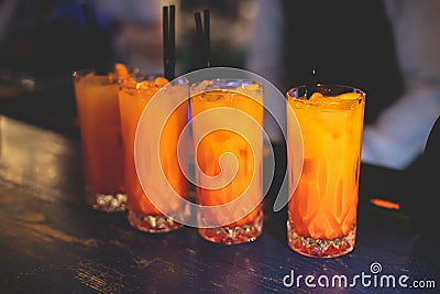 View of alcohol on a party, row line of orange red colored aperitif alcohol cocktails on a party, tequila sunrise, mimosa, spritz Stock Photo