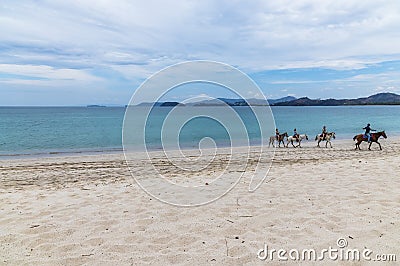 A view along the beach towards horse riders at Tamarindo Stock Photo