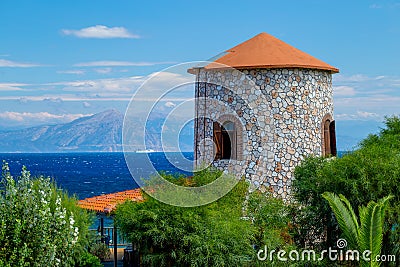 View of the Ancient Greek Windmill Tower and the Sea with Ship and Distant Coastline Stock Photo