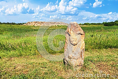 View of the ancient kurgan stela, stone idol against the backdrop of ancient mound of sandstone boulders Stock Photo