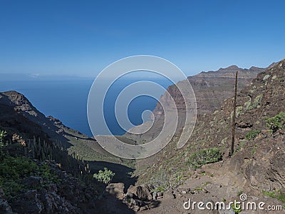 View of arid subtropical landscape of Barranco de Guigui Grande ravine with cacti and palm trees viewed from hiking Stock Photo