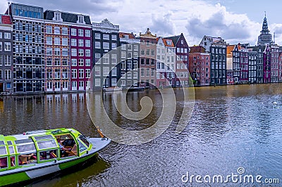 View of authentic Amsterdam canal houses , from the water , where a tour boat sails . Editorial Stock Photo