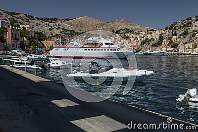 View of the bay of Symi island. A ship, passenger boats and yachts on a background of hills. Shadow and light on the water Stock Photo