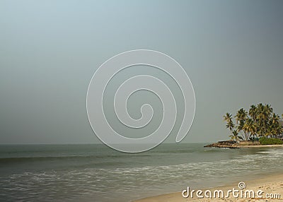 View from the beach with breakwater rocks and coconut trees in the background Stock Photo