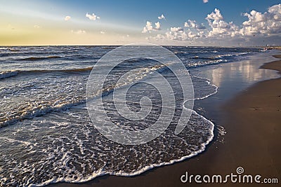 View from the beach on the white foam cups of the rising waves at high tide in the North Sea, all this at sunset Stock Photo