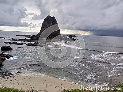 the view of a beach with white sand, small waves and surrounded by beautiful rocky hills Stock Photo