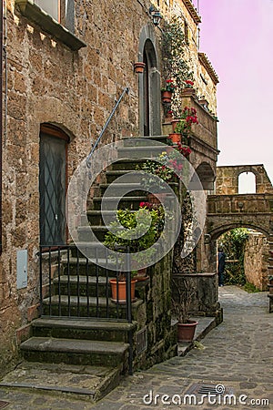 View of beautiful alley with flowers in the historic center of Civita di Bagnoregio village at sunset, Lazio Editorial Stock Photo